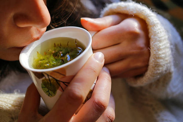 A young woman on the couch and with sage tea on the hand.